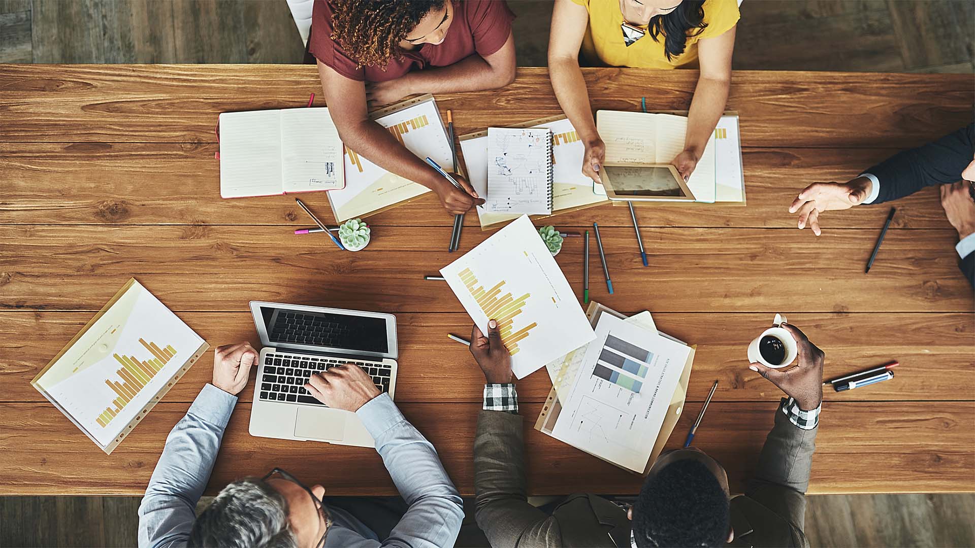 birds eye view people around a meeting table looks at charts
