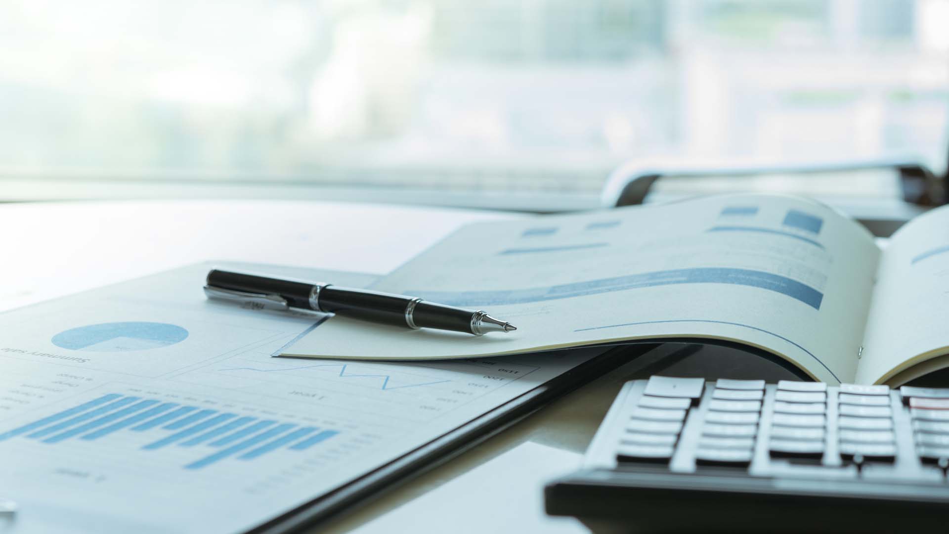 Paper with charts, a pen, and a calculator on a table