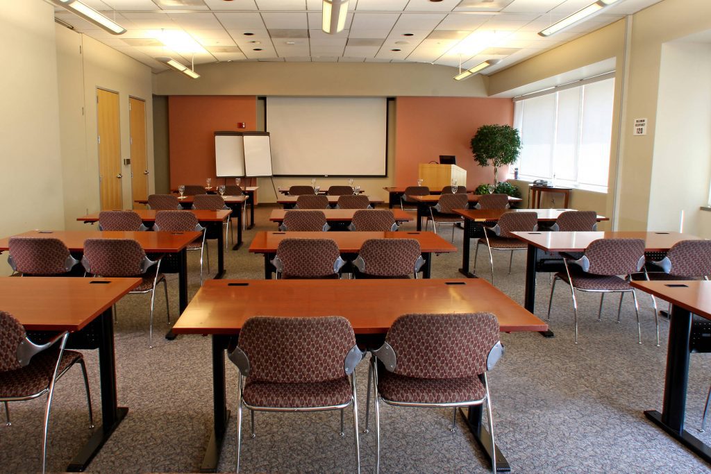 Large conference room with desks, chairs and a projector screen