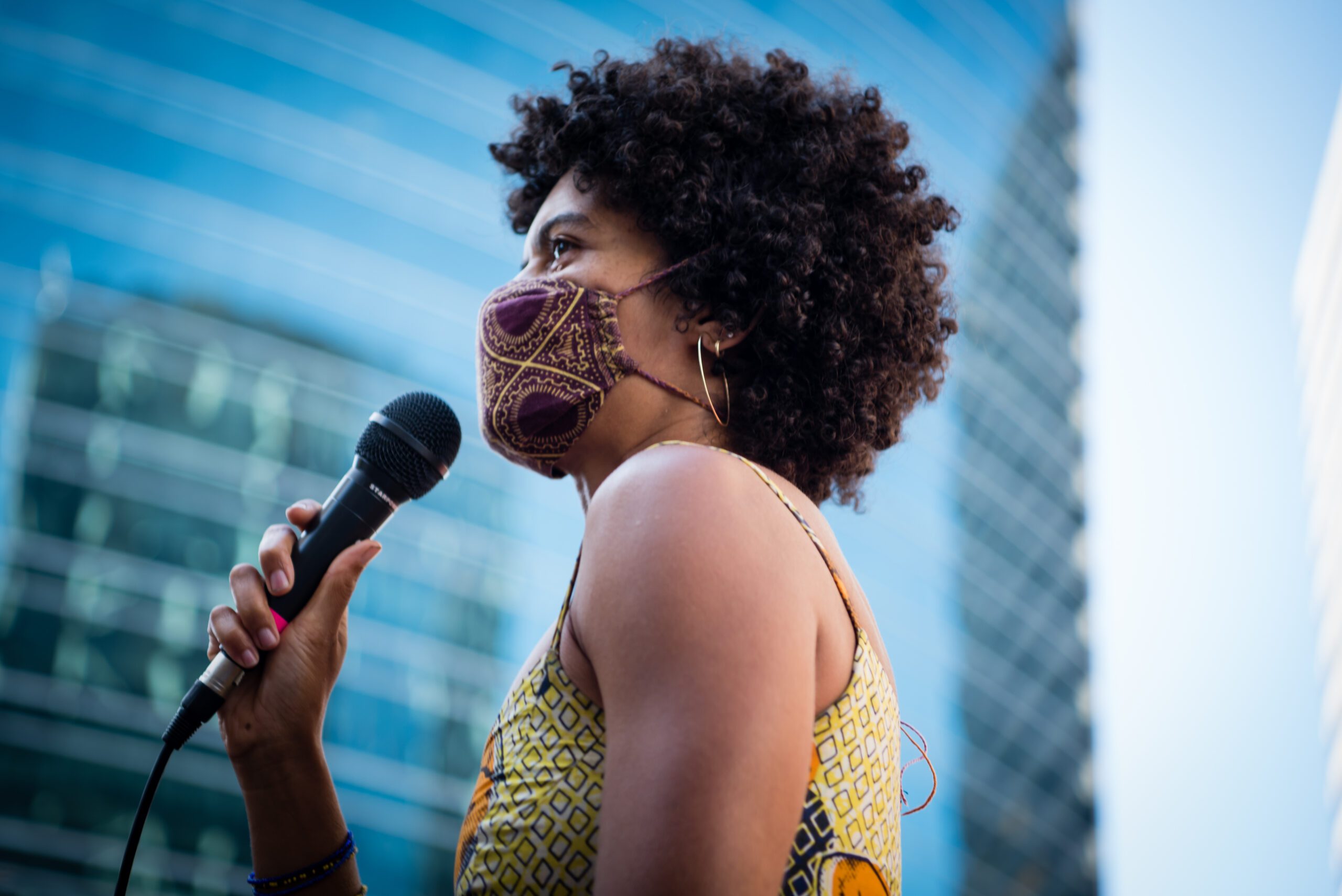Woman wearing a mask and speaking into a microphone